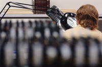 Un técnico está observando a través de una lupa con iluminación, sentado entre varios bancos de trabajo.