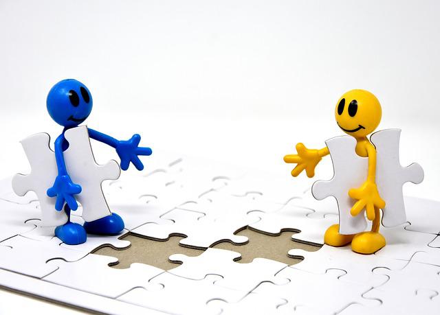 Dos muñecos encajando piezas en puzzle.