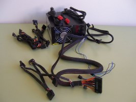 Vista de una fuente de alimentación de la que salen sus cables con sus conectores y el resto de cables que pueden utilizarse según las necesidades. 