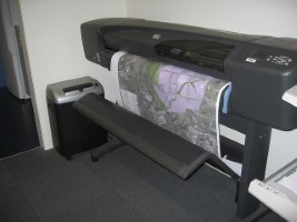 Muestra un plotter imprimiendo un cartel gráfico de gran tamaño.