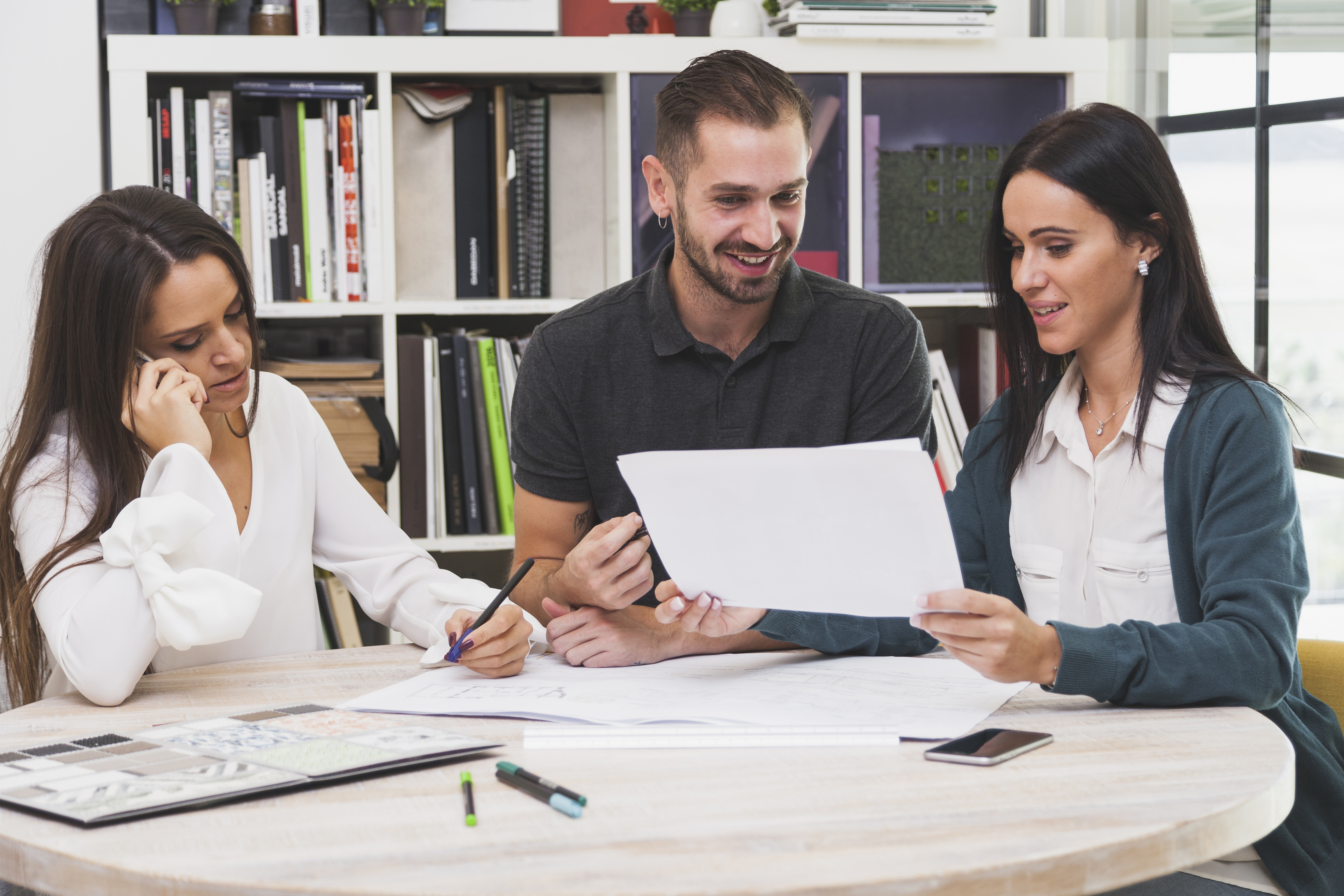 En la imagen se observa a tres compañeros trabajando en equipo.